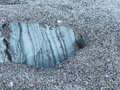 From above of droughty fine sand with cracked stone on seashore in evening