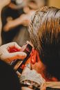 Crop tattooed barber trimming hair of anonymous male client in modern beauty salon