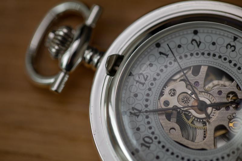 Skeleton pocket watch with an exposed movement on a wooden surface — photo by David Roberts on Pexels