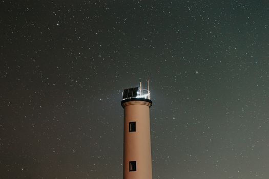 在晴朗的星空下，一座宁静的灯塔在夜晚散发出柔和的光芒