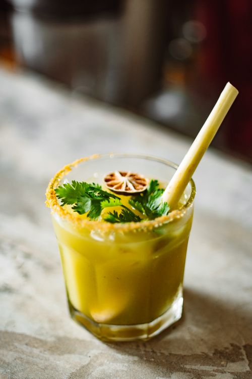 Free Vibrant citrus cocktail garnished with herbs and a slice of dried lime served in a glass. Stock Photo