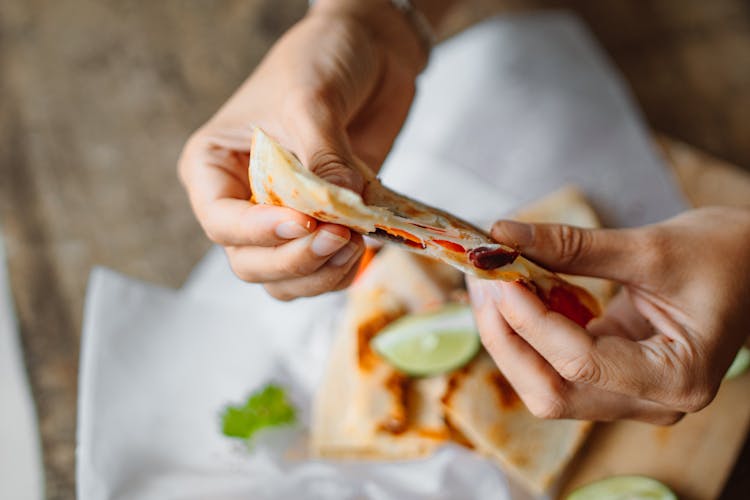 Person Holding A Sliced Tortilla Wrap With Filling