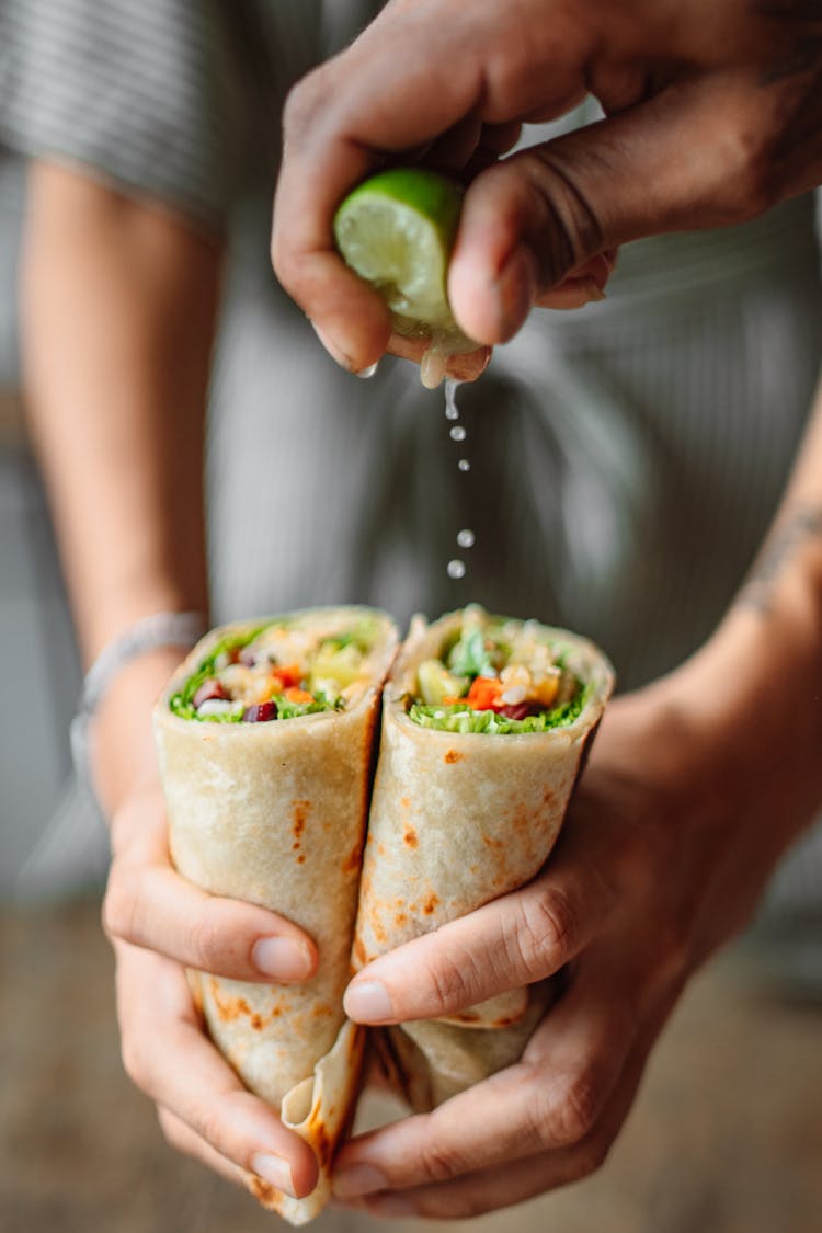 Person Squeezing Lime On Vegetable Wrap