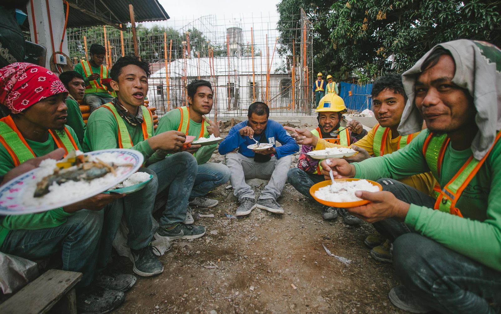 Group of people sharing a communal meal seated on the ground in the traditional kamayan style of eating with hands