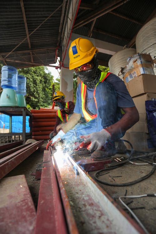 Free Man in Blue Shirt and Yellow Hard Hat Welding a Metal  Stock Photo