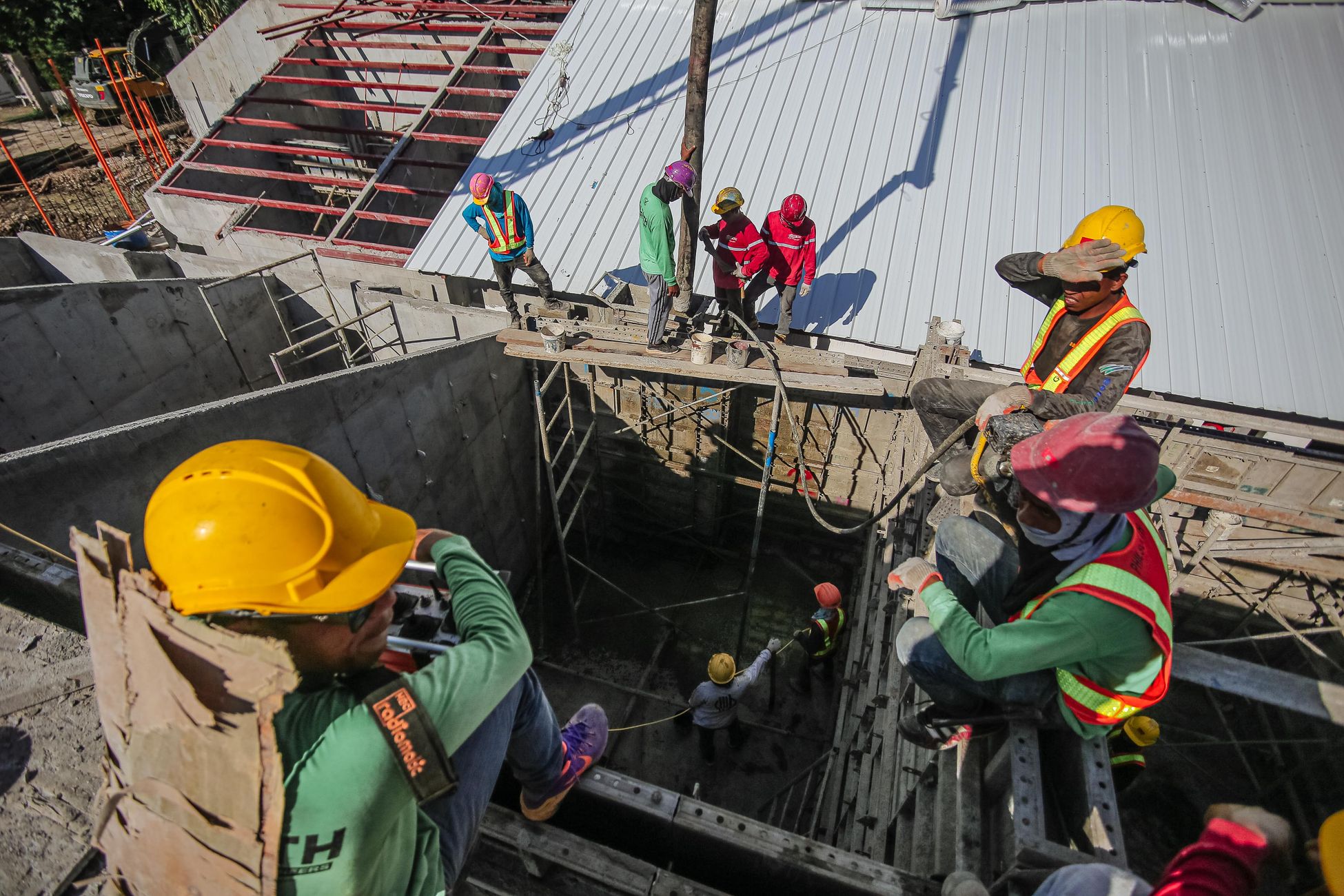 Construction workers wearing helmets and vests on a busy site, focusing on safety and teamwork.