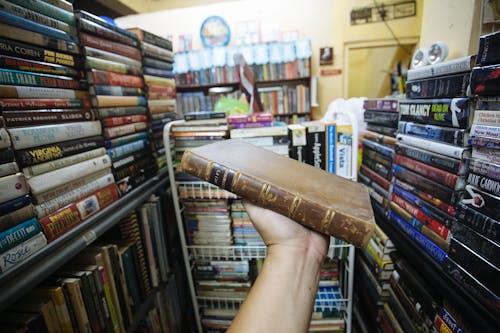 Person Holding a Brown Old Book 