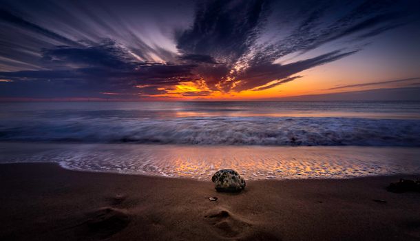 A breathtaking view of a sunset over a tranquil beach with gentle waves hitting the shore.