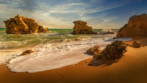 Free Scenic beach landscape with rocks, waves, and sunset for serene travel inspiration. Stock Photo