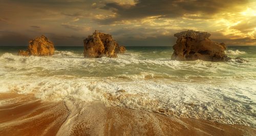 Free Stunning seascape during golden hour with dramatic waves crashing against rock formations. Stock Photo