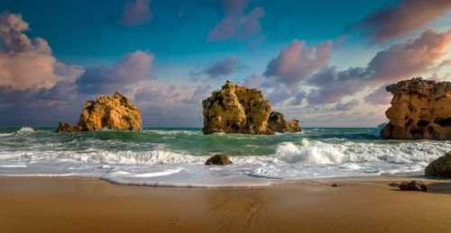 Free Stunning seascape featuring crashing waves against unique rocky formations under a vivid sky. Stock Photo