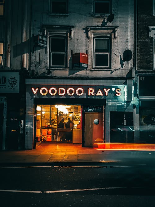 Free Entrance of modern cafe with glowing signboard and glass walls located in aged building on city street at night Stock Photo