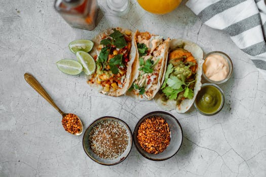 Top view of colorful Mexican tacos with limes, spices, and sauces, perfect for a culinary splash.