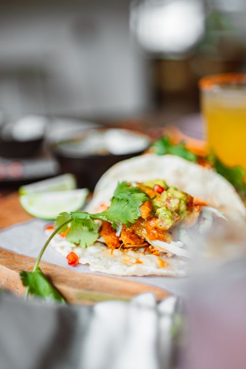 Free Close-up of a chicken taco with avocado and lime on a wooden board. Stock Photo