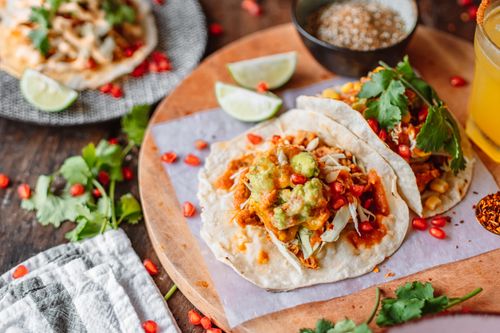 Free Delicious Mexican tacos topped with fresh guacamole and lime, perfect for a vibrant and flavorful meal. Stock Photo