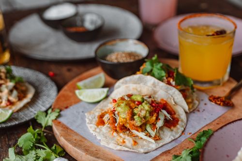 Free Delicious Mexican tacos with fresh guacamole, lime, and chili on a rustic wooden board. Stock Photo