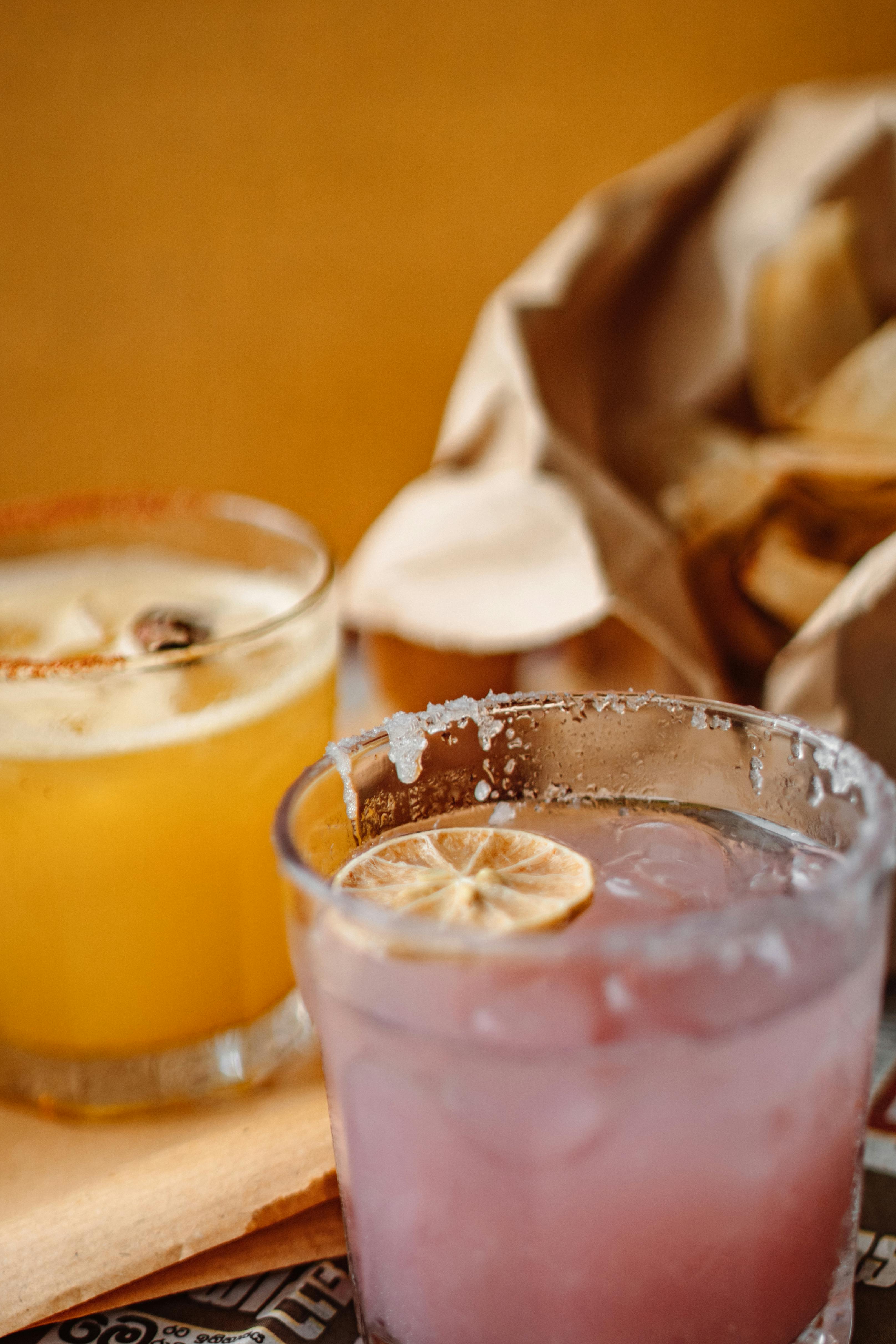 两杯充满活力的鸡尾酒，配以酸橙装饰，并附送一袋脆片