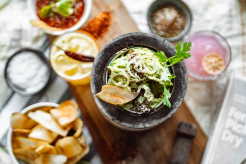 Free Vibrant, appetizing spread featuring guacamole and dips with chips on a wooden board. Stock Photo