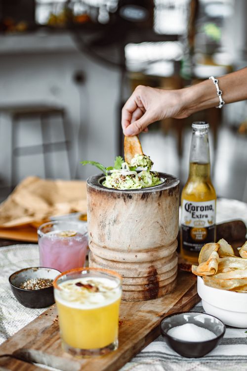 Free Hand reaching into vibrant bar snack scene with Corona beer and cocktails. Stock Photo