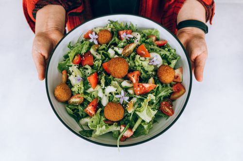 Free A vibrant fresh salad with crispy falafel, tomatoes, cucumbers, and purple flowers. Stock Photo