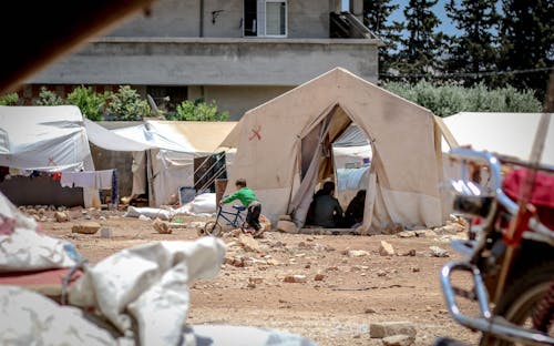 Temporary fabric tents located on ground with garbage in poor district for refugee camp