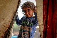 Cheerful ethnic kid standing in doorway of tent