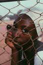 Black woman in turban behind wire fence