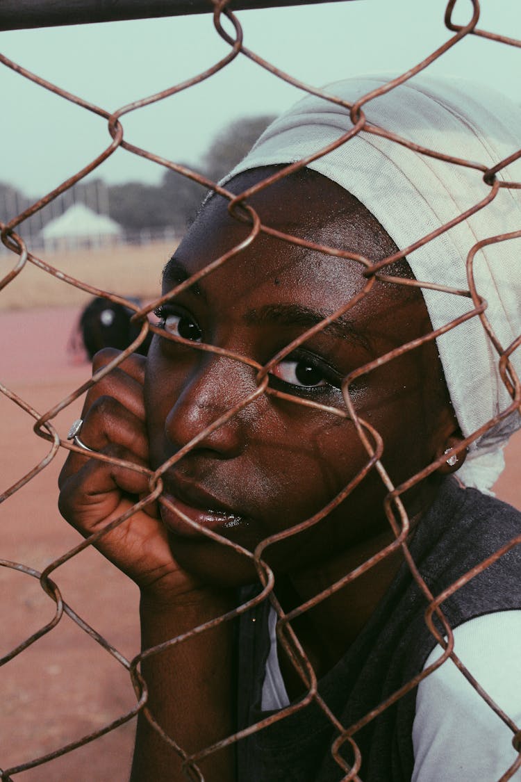 Black Woman In Turban Behind Wire Fence