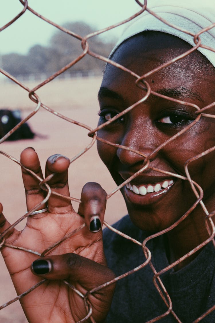 Smiling Black Woman Behind Chain Link Fence