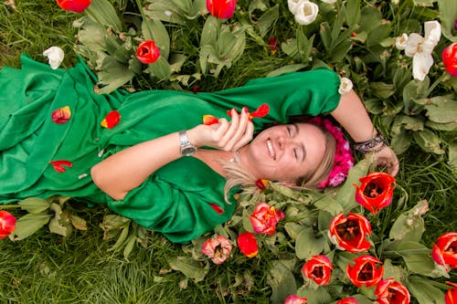 A Woman in Green Dress Lying on Green Grass Field