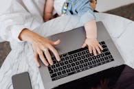 从俯视角度看，一位母亲正和幼儿一起在笔记本电脑前工作