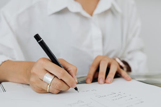 笔记本上，用黑色笔书写的手的详细特写