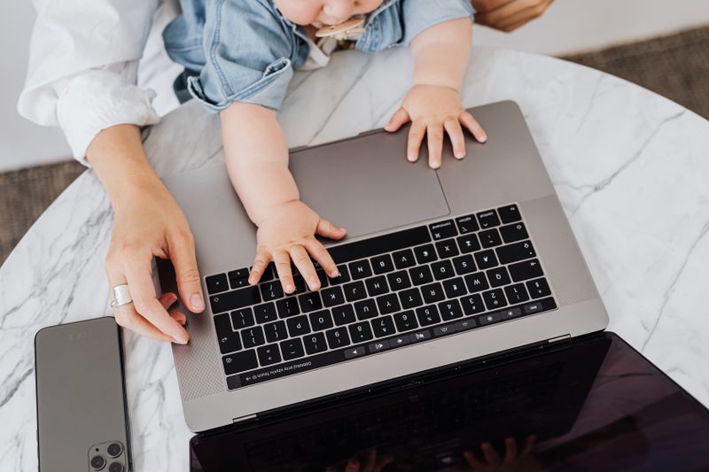 parent wearing large headphones at a desk with a child nearby