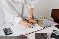 一位女士在大理石办公桌前的笔记本上做设计，旁边放着技术和材料