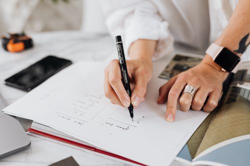 Free Close-up of a female hand writing on paper in an office environment with a focus on productivity. Stock Photo