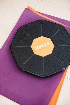 Black balance board on purple exercise mat for fitness and wellness indoors.