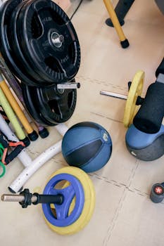 Assorted gym equipment including weights and kettlebells arranged indoors for varied workouts.