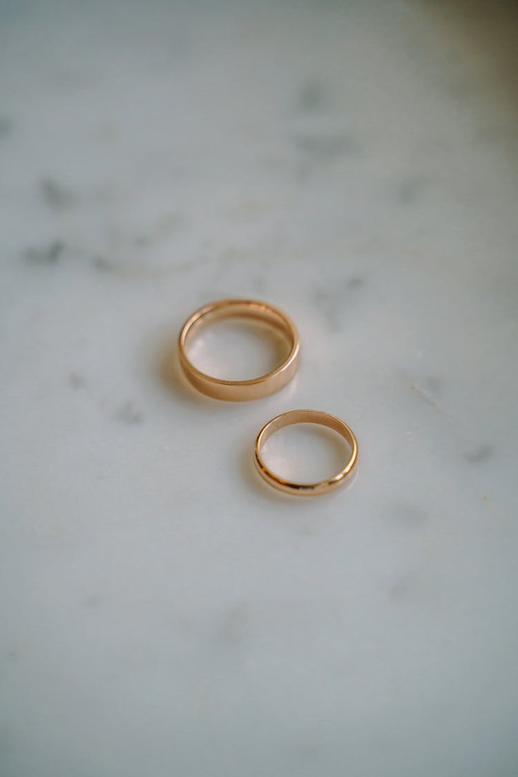 Golden Wedding Rings Placed On Marble Table