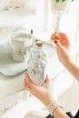 From above of crop anonymous young bride with pearl bracelet holding decorative glass bottle in hand before wedding ceremony