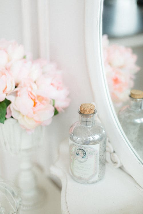 白いテーブルの上に置かれた芳香のピンクの花と装飾的なボトルと花瓶