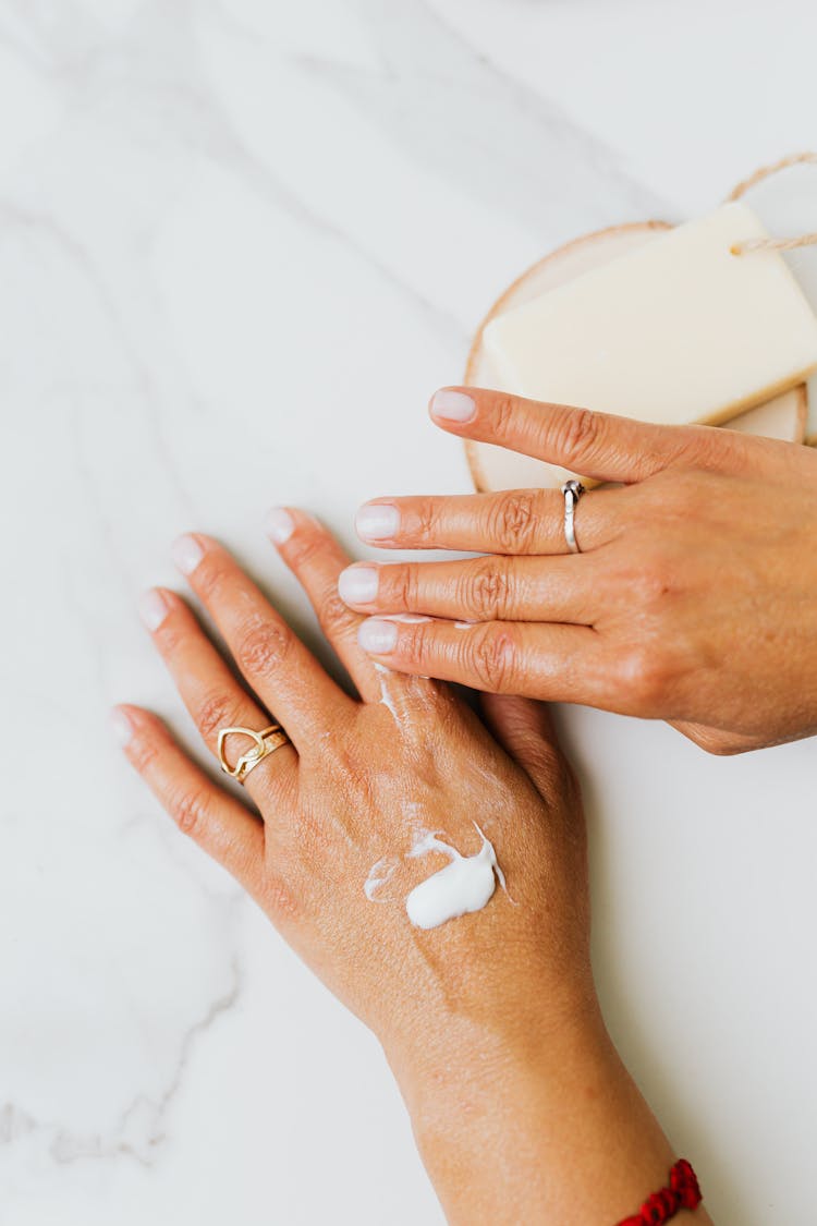 Photo Of White Lotion On A Person's Hand