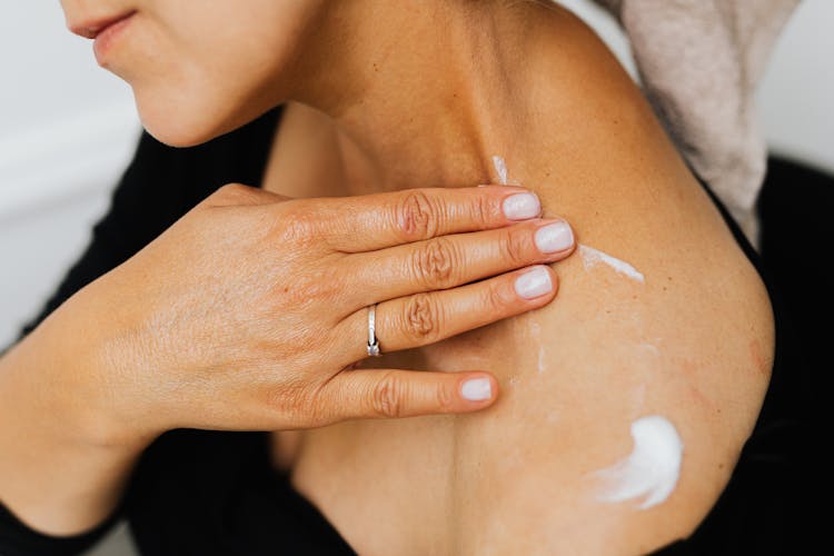 A Woman Applying Lotion Cream On Her Skin