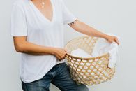 Woman in White V Neck Shirt and Blue Denim Jeans Holding Brown and White Woven Basket