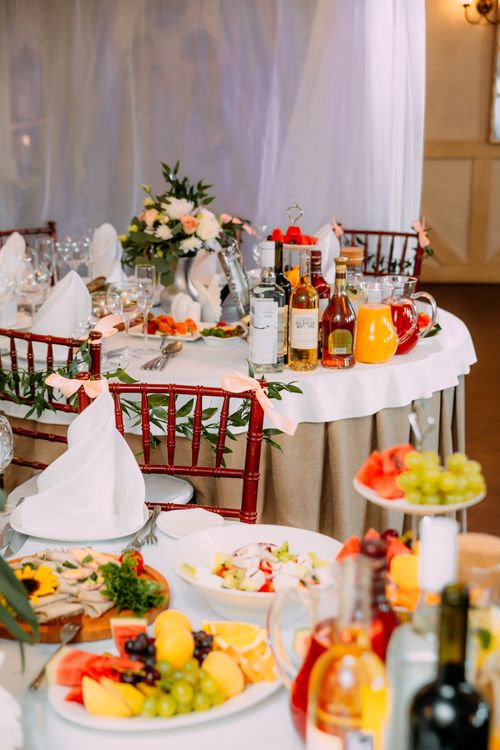 Free Tables decorated with fresh flowers with fruits and bottle of drinks in restaurant for occasion Stock Photo