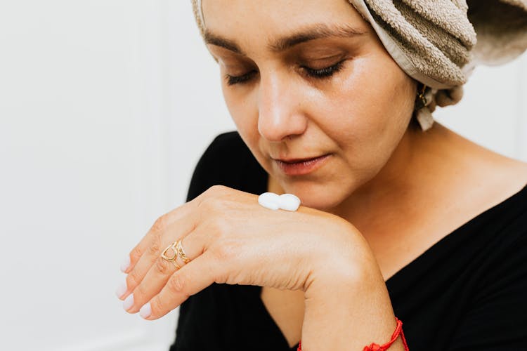 A Woman With Lotion Cream On Her Hand