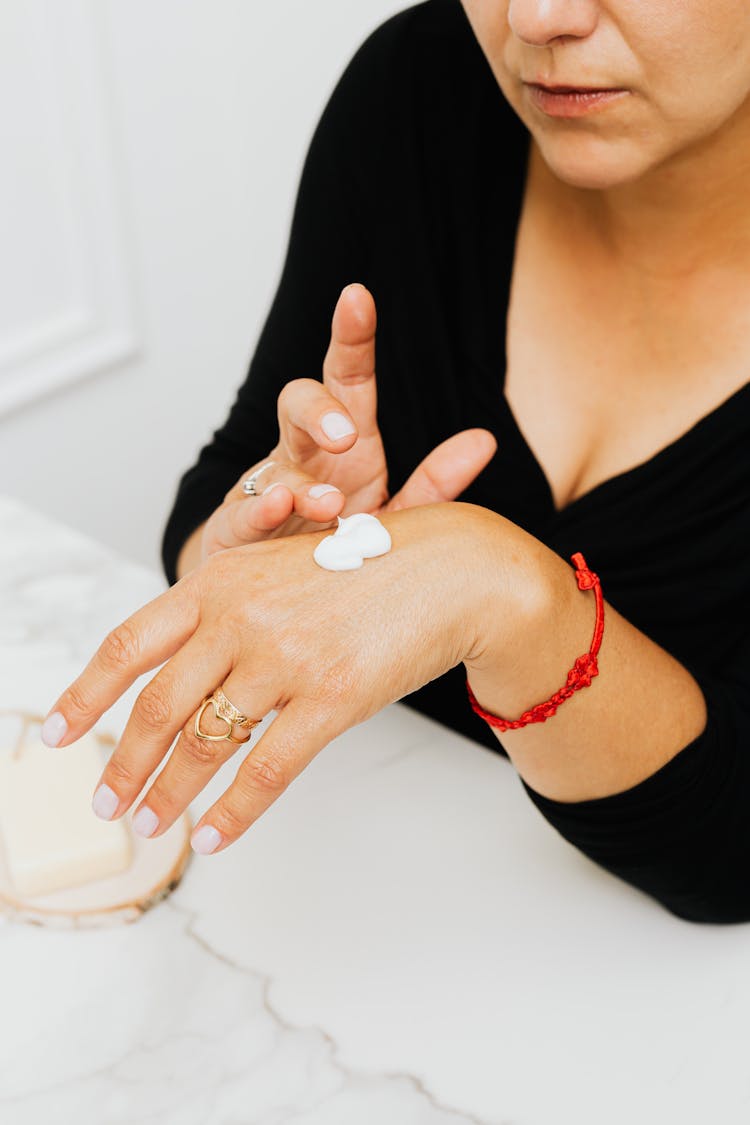 A Woman In Black Long Sleeves With Lotion Cream On Her Hand