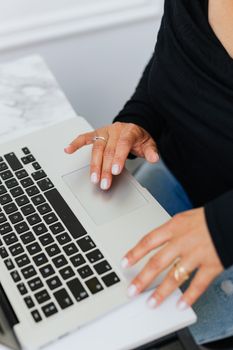 Close-up of a woman using a laptop touchpad in a modern office setting.