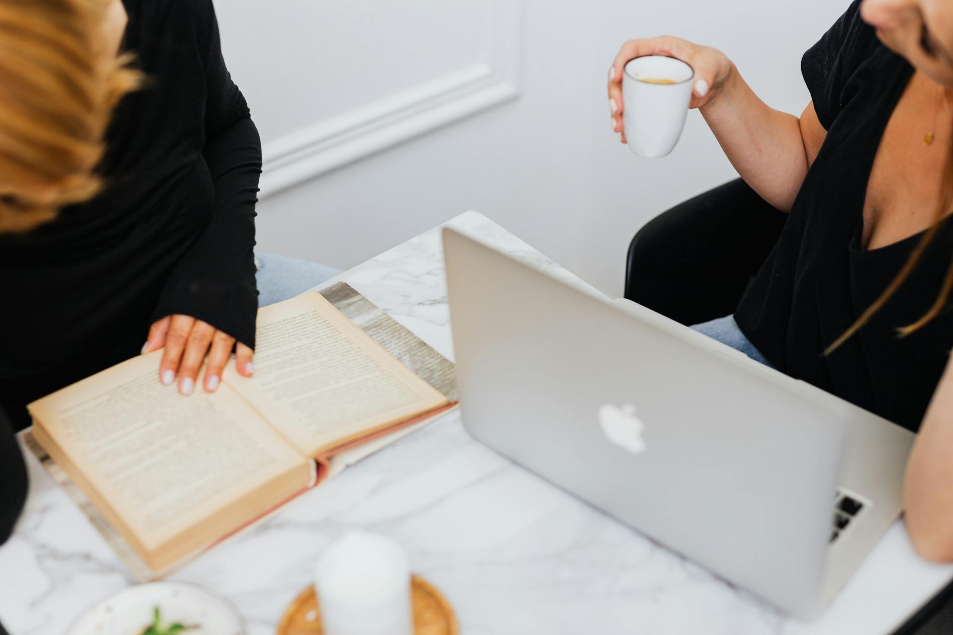 Two people relaxing with a laptop and tea on a marble table in a modern office setting.