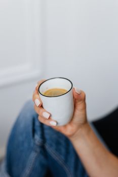 特写镜头中，一位女士的手正拿着一杯陶瓷咖啡杯，捕捉着放松的瞬间