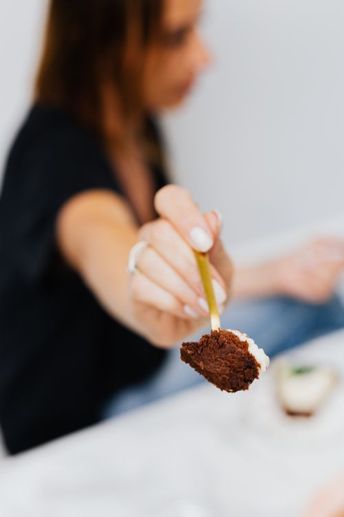 Free Focused shot of a brownie on a spoon held by a woman, with soft blurred background. Stock Photo